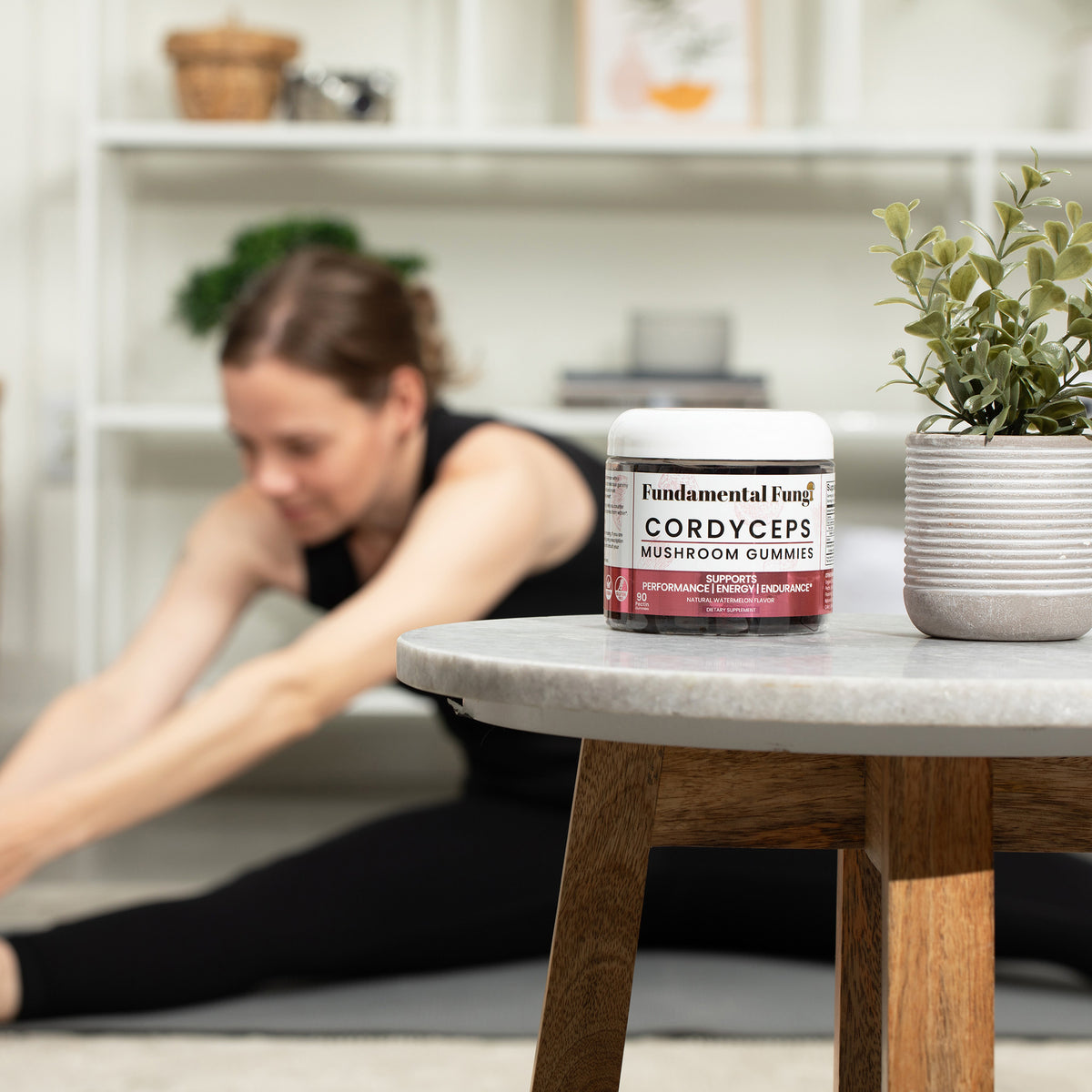 Woman stretching at home with Cordyceps Mushroom Gummies on a side table