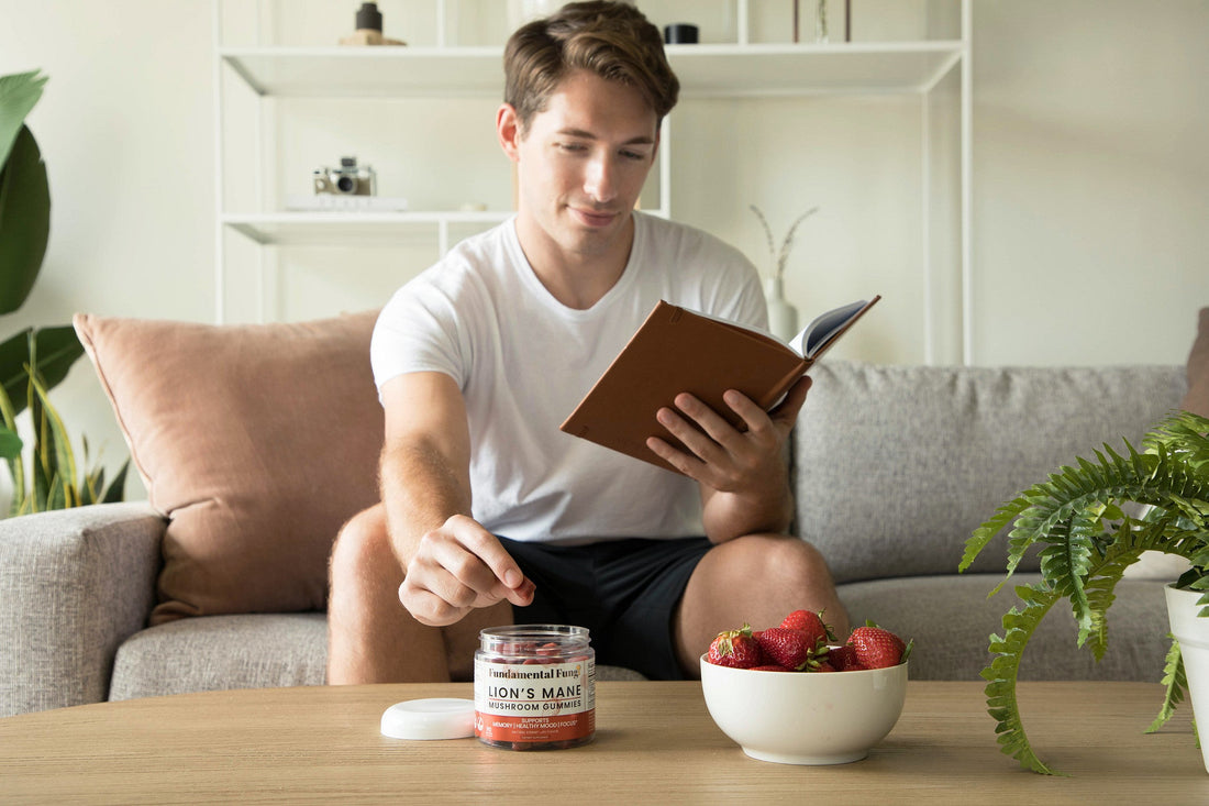 Man reading a book and taking a Lion's Mane mushroom gummy as part of his routine