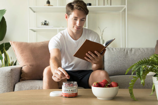 Man reading a book and taking a Lion's Mane mushroom gummy as part of his routine