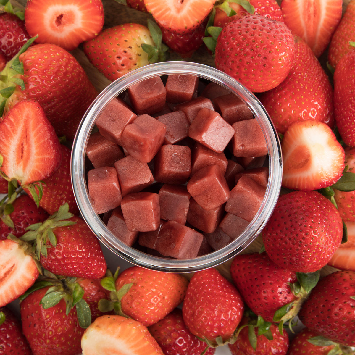 Lion's Mane mushroom gummies in a glass jar surrounded by fresh strawberries