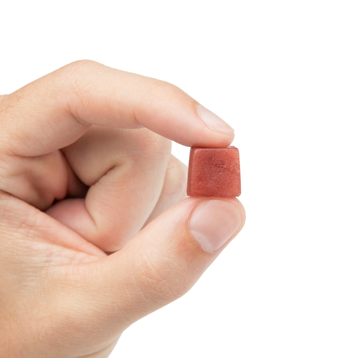 A single strawberry Lion's Mane mushroom gummy held between two fingers